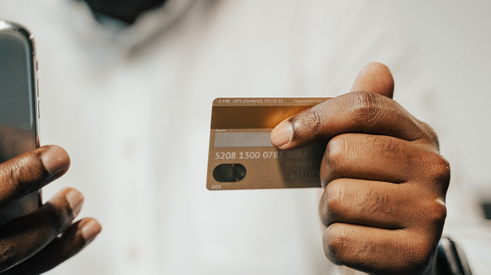 ] Hands holding a debit card and a cell phone