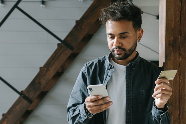 man holding debit card and downloading an app on his phone
