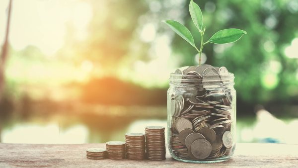 Piles of coins growing and sprouting in a glass jar