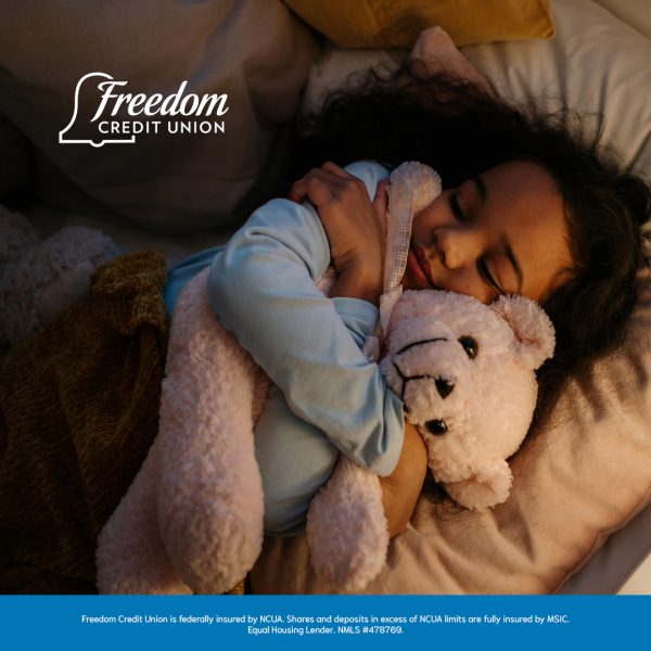 child in a bed hugging a teddy bear