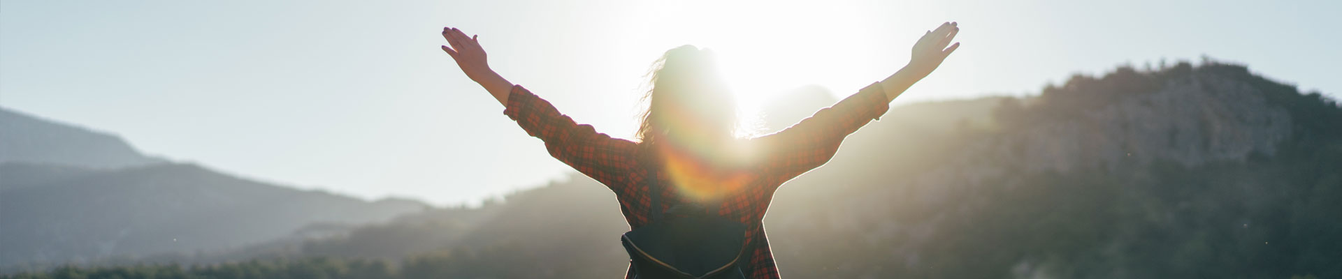 Woman holding up hands on top of mountain