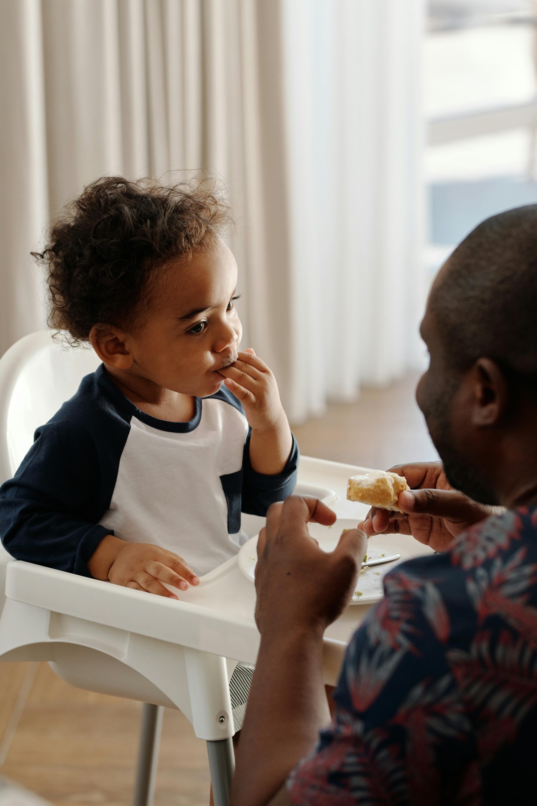 Father feeding child in a highchair