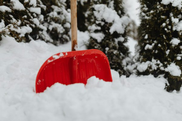 red snow shovel stuck in a mound of snow